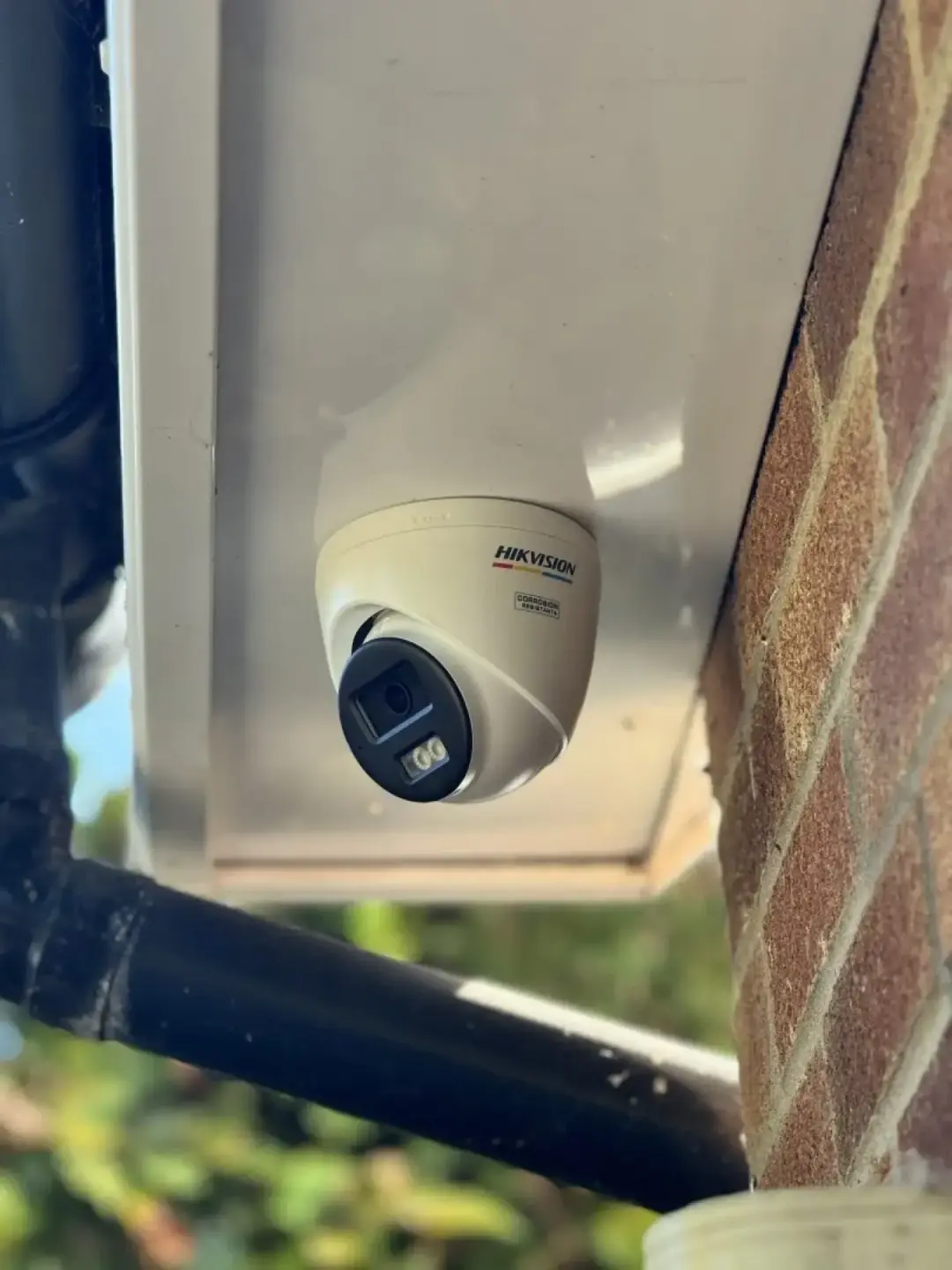 A Hikvision turret camera fitted under the eaves beside a downpipe
