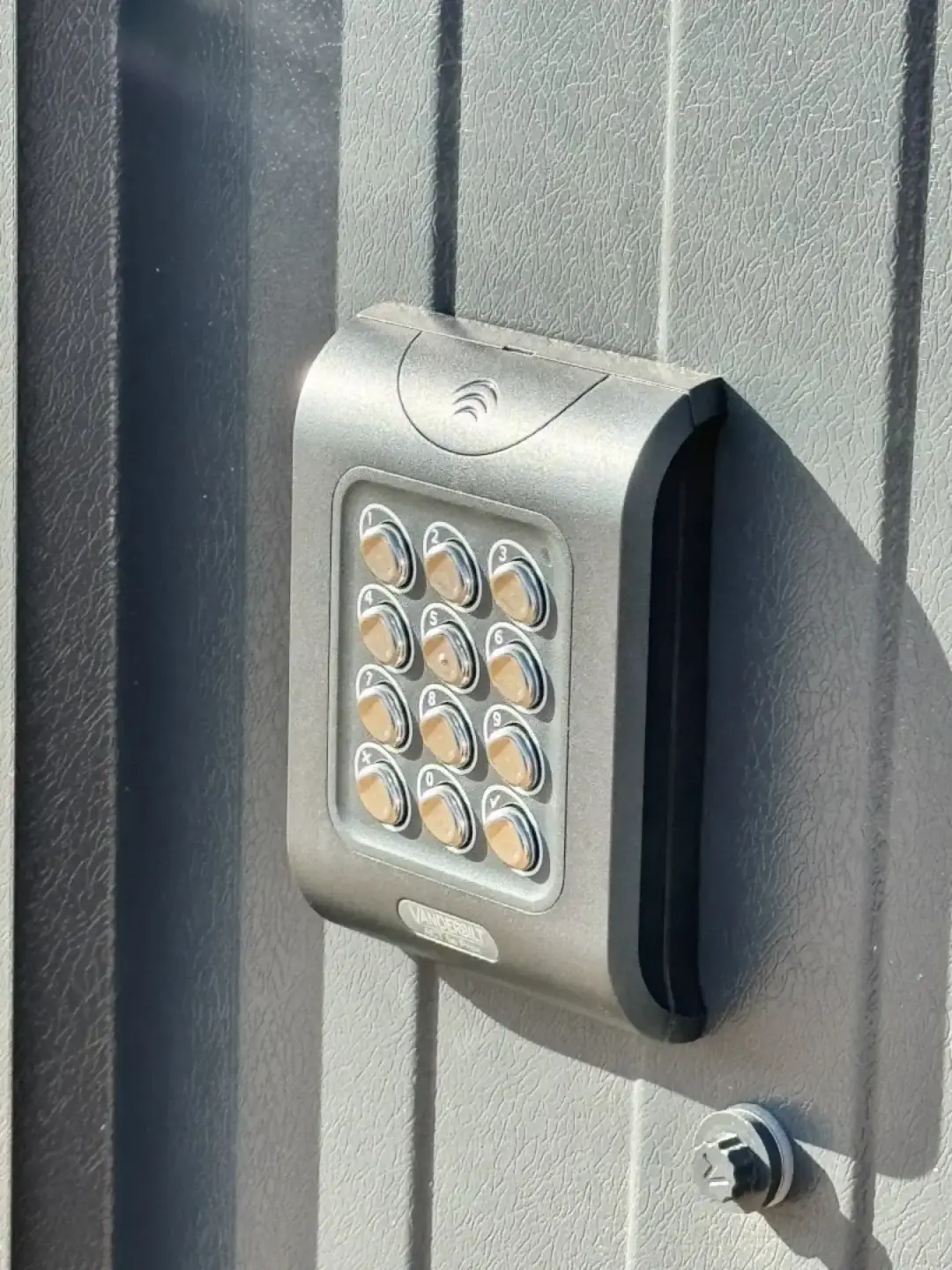An illuminated access control keypad and card reader on a grey clad wall