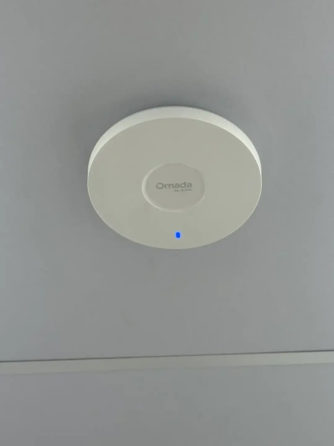 A ceiling mounted wireless access point on a white ceiling