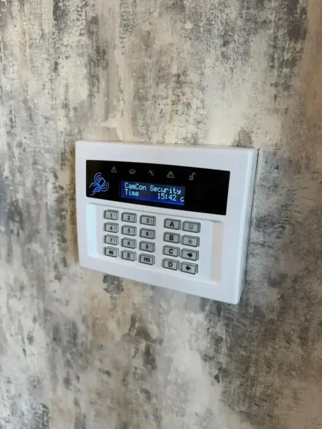 A Camcon Security intruder alarm keypad fitted to a rendered wall